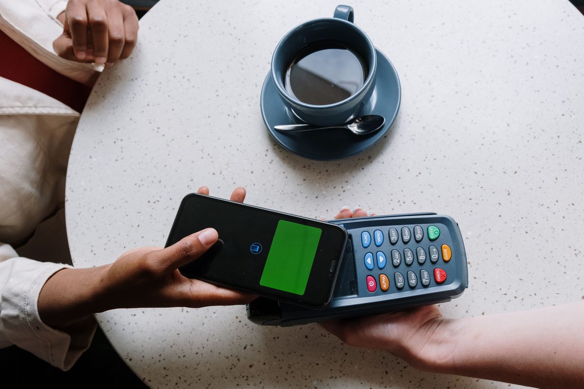 Person using smartphone for instant P2P money transfer and contactless payment at POS terminal